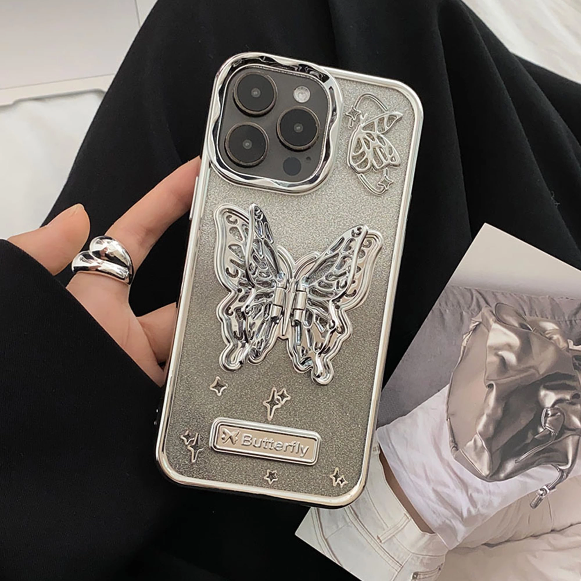قاب آیفون Butterfly Stand Case متالیک با پروانه فلزی استندی و بال‌های متحرک روی زمینه شاین نقره‌ای